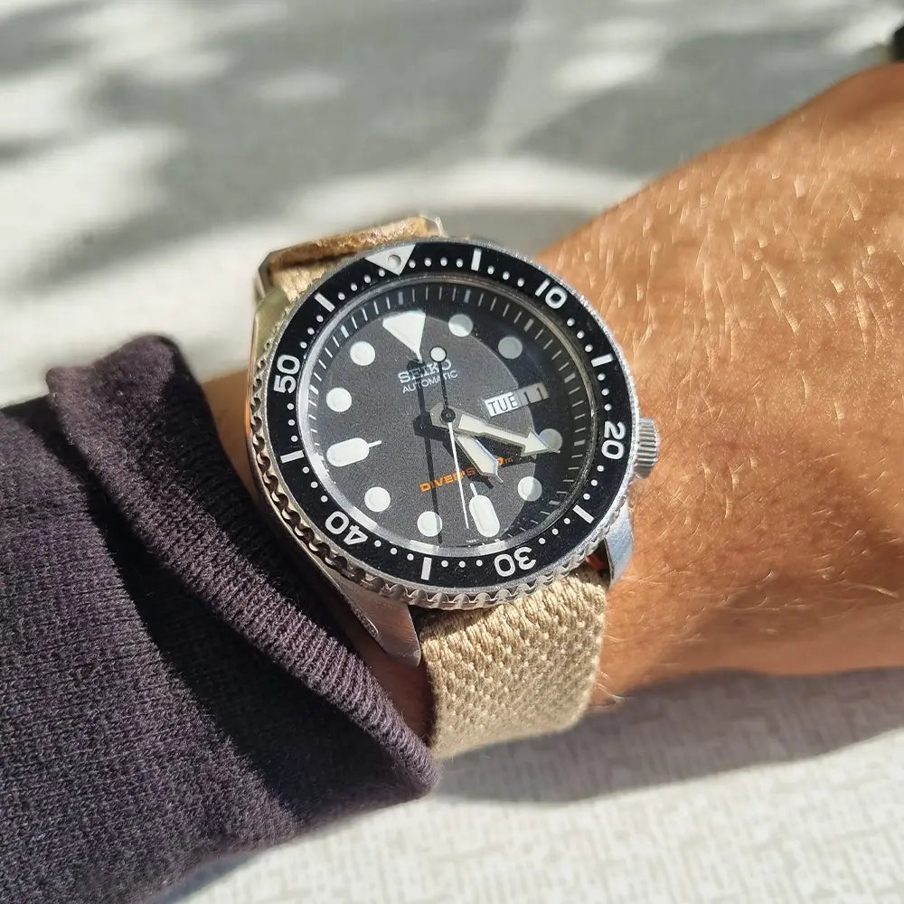 En handled med en Seiko SKX007 som har ett natoband i beige färg