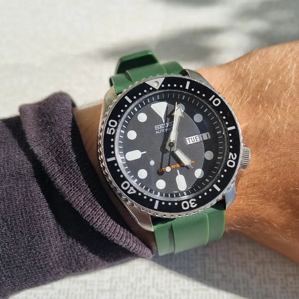 En Seiko SKX007 med grönt armband av gummi på handled