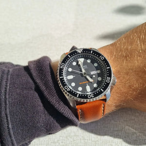 En handled med en Seiko SKX007 på ljusbrunt läderband