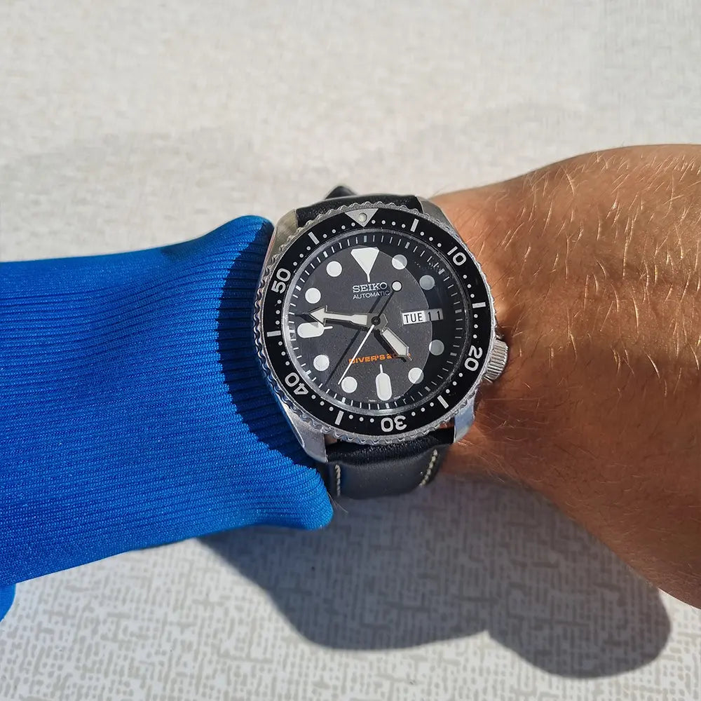 En Seiko SKX007 med svart klockarmband av läder på en handled